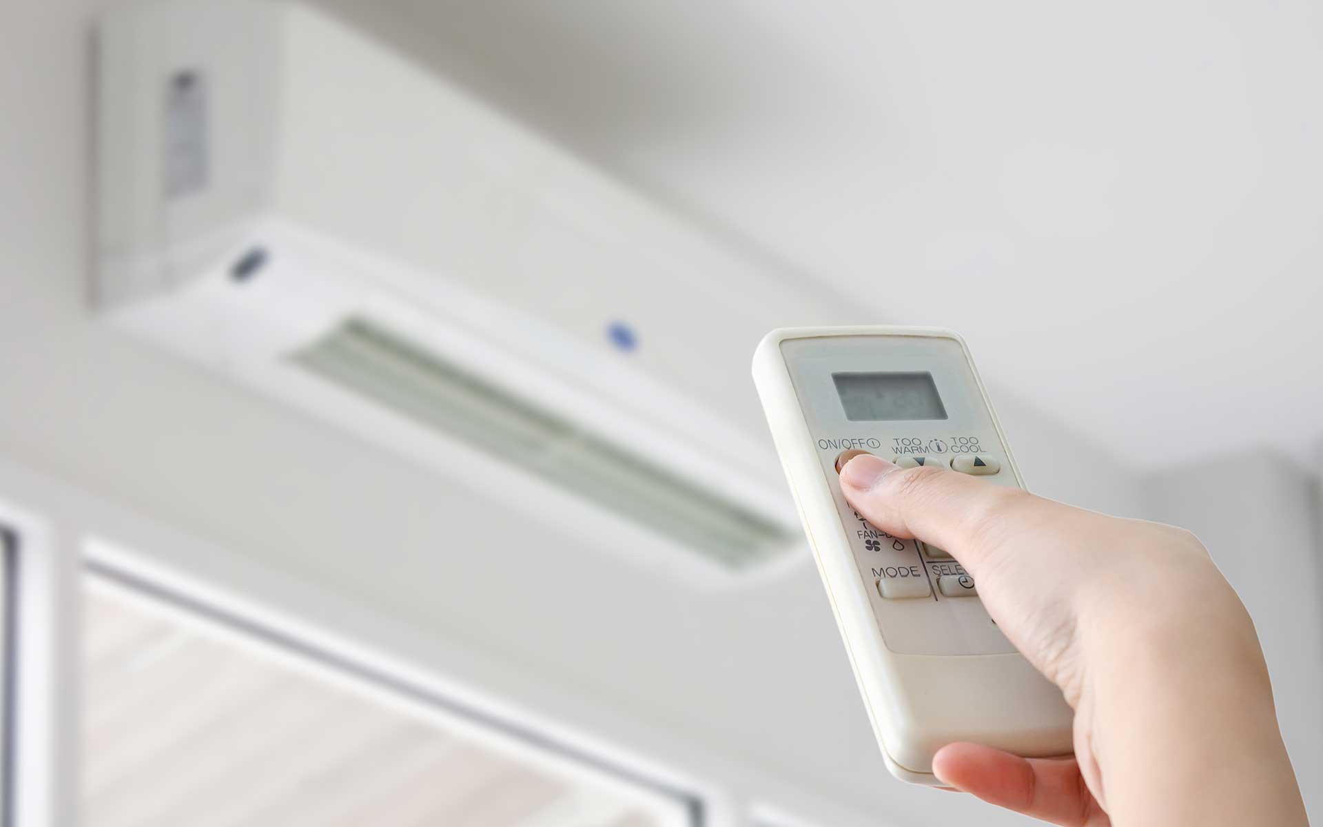 Image - Person using remote control to power on a heating and cooling unit