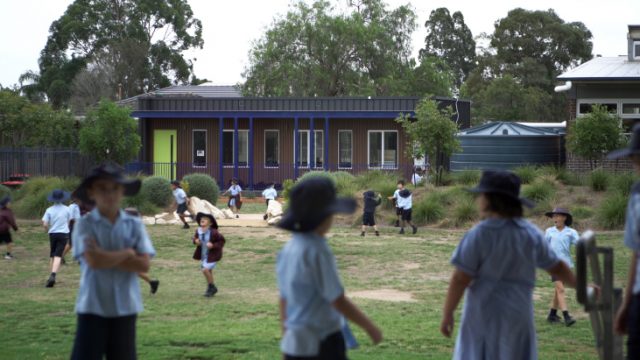 Children playing in the school yard with the HIVVE portable classroom in the background